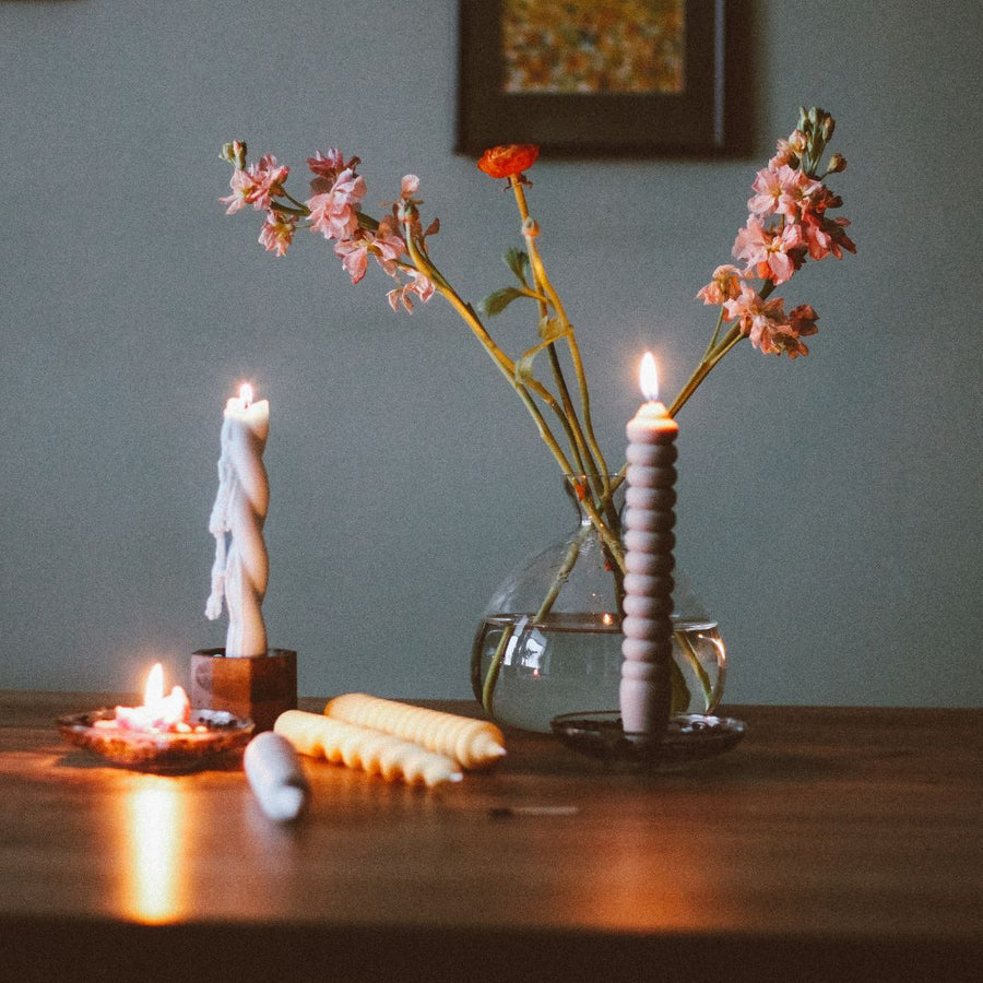 Lit decorative candles beside pink flowers in a glass vase